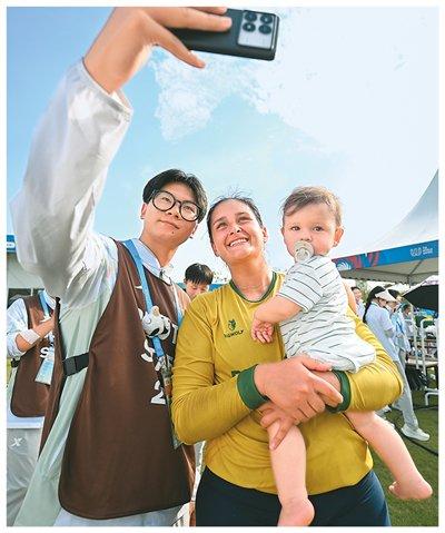 浮士德球女子决赛中，巴西队战胜瑞士队获得冠军。图为巴西队球员萨比娜·祖费特在赛后抱着11个月大的孩子与志愿者合影。